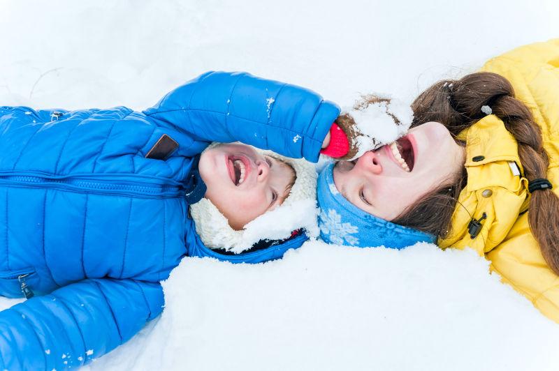 快乐的母亲和孩子躺在冬日的雪上玩耍