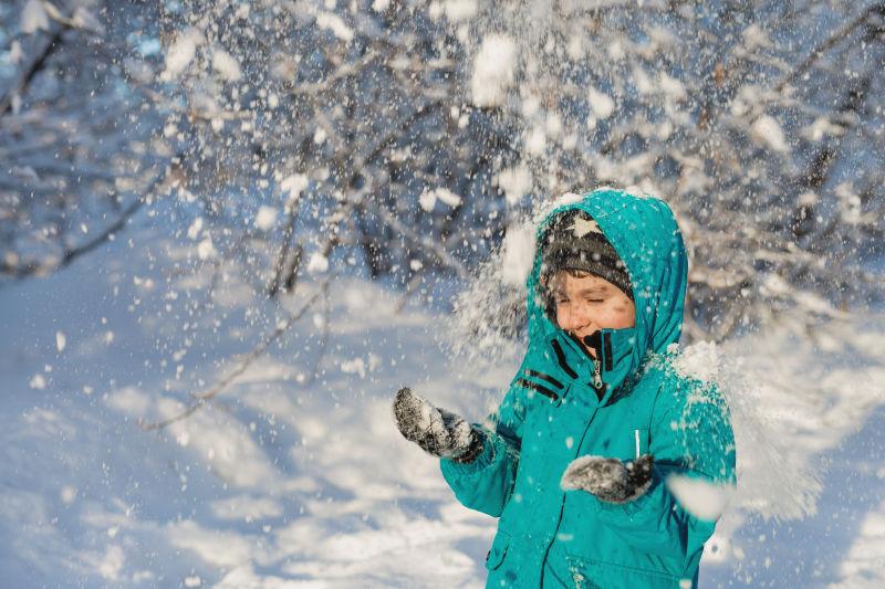 一个可爱的小男孩站在雪下