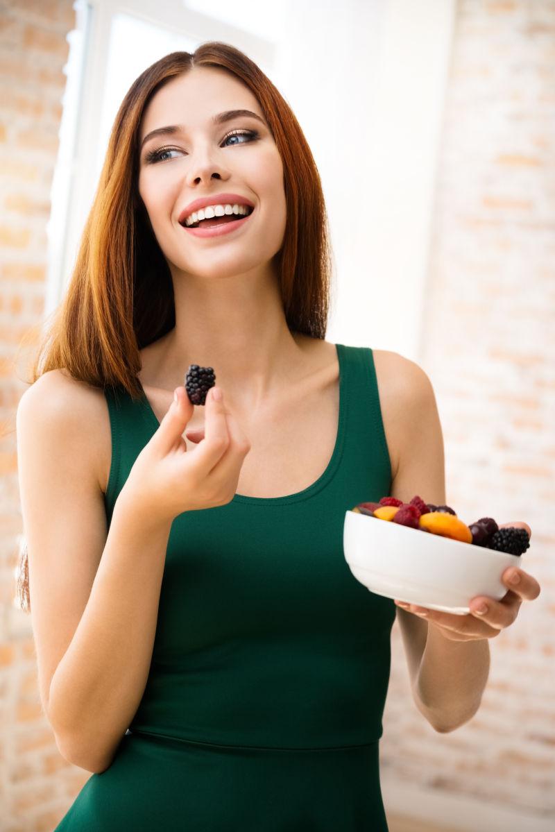 年轻快乐微笑的女人吃着水果