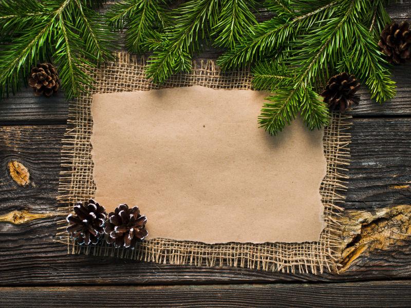 木板上的空白圣诞贺卡和圣诞树枝还有松果