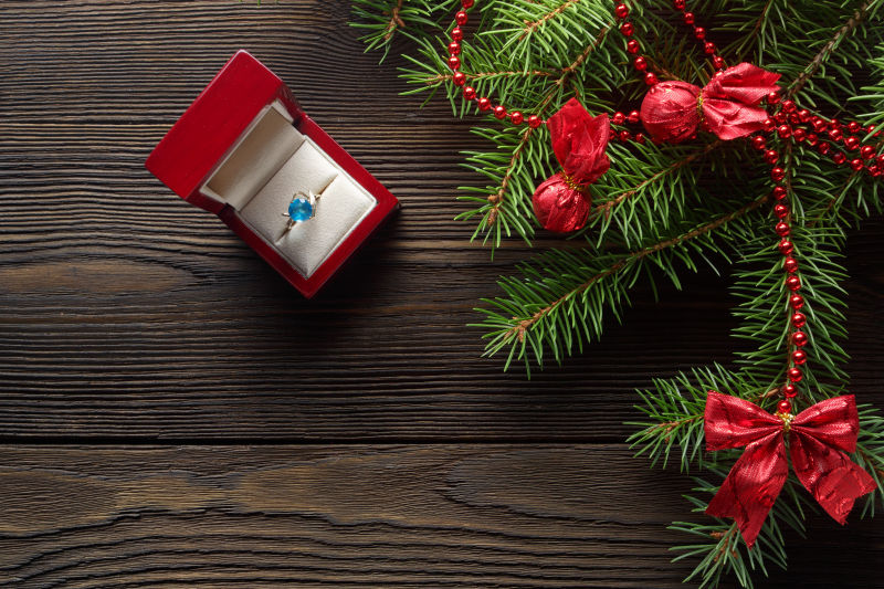 木板上的圣诞花环和礼物盒子里的戒指