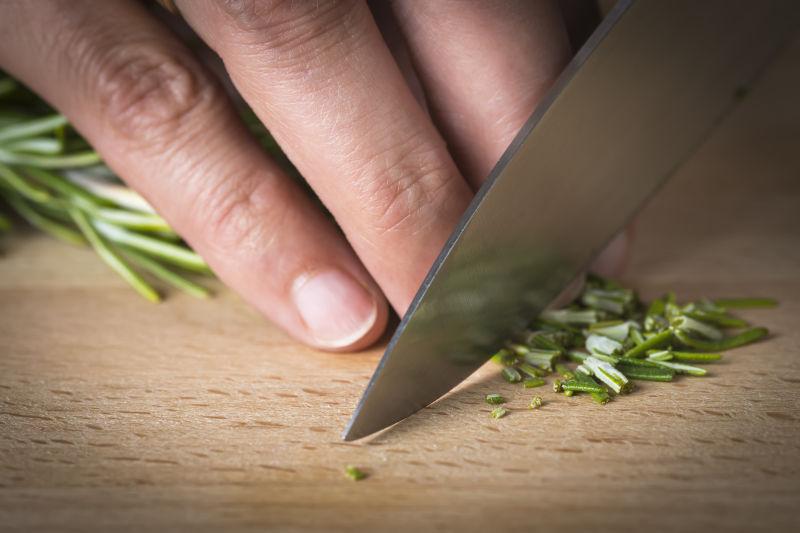 厨师在刀架上用刀切碎迷迭香枝