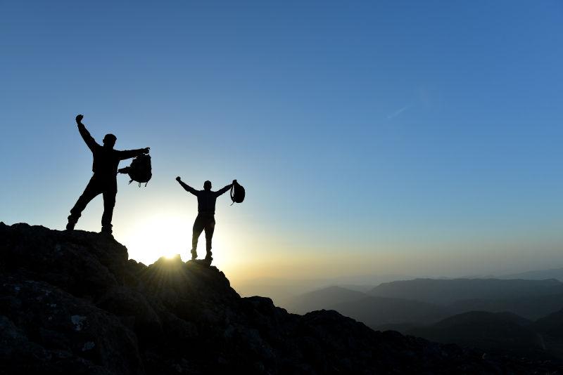 山顶上看着日出欢呼的两个年轻人