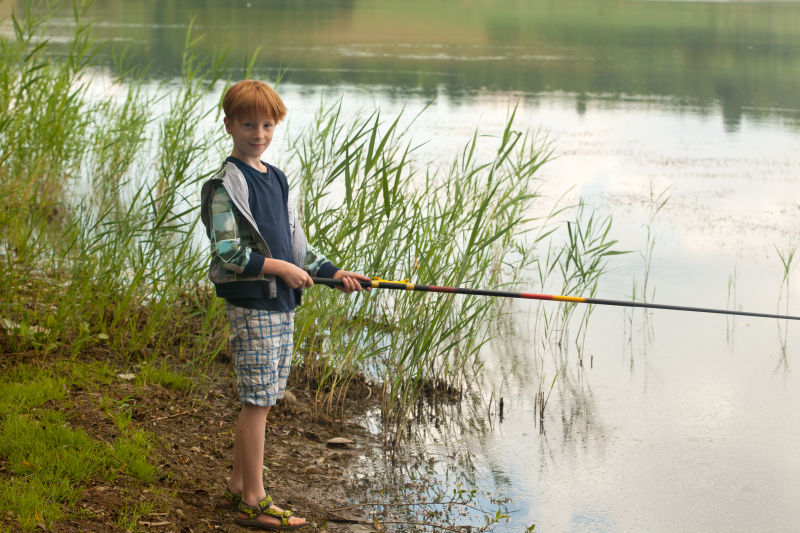 站在岸边钓鱼的小男孩