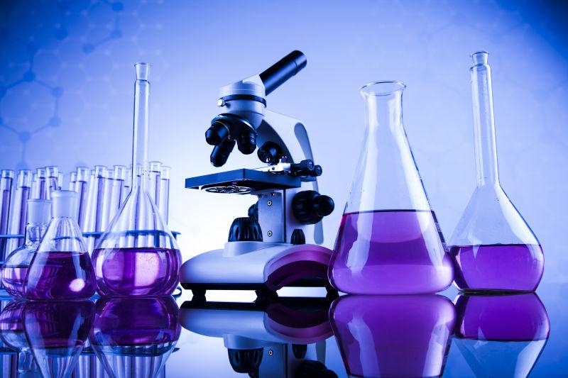 蓝色背景上的显微镜和装着紫色液体的实验器皿