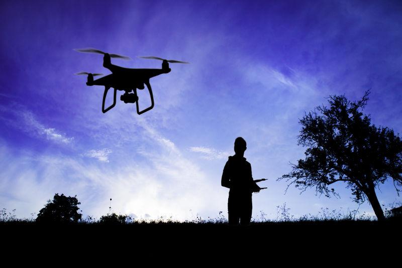 草地上男人要遥控器操控着空中的无人机