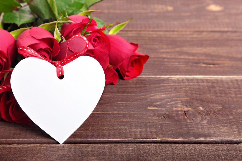 木桌上的情人节玫瑰与白色礼品标签