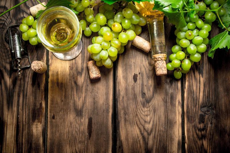 木桌上的白葡萄酒和葡萄