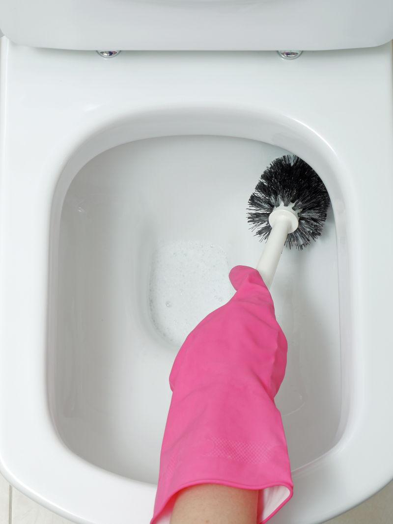 戴着粉色手套的家庭主妇在清洗马桶
