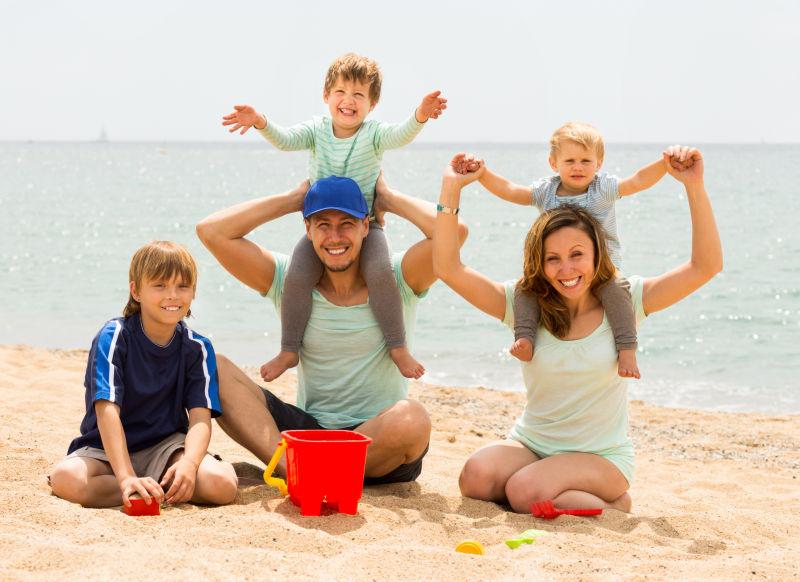 快乐的父母和孩子们在沙滩上玩耍