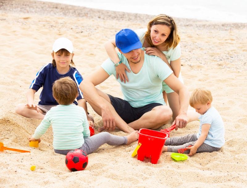 微笑的父母和孩子们在沙滩上休息玩耍