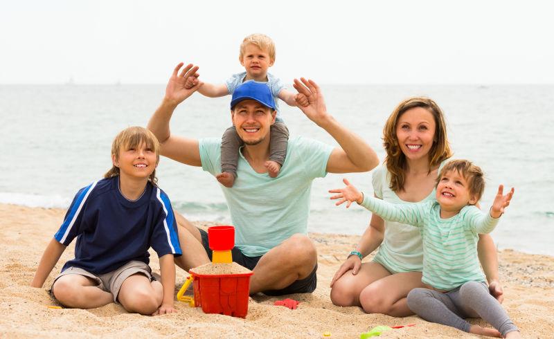 快乐微笑的五口之家在海边玩沙子