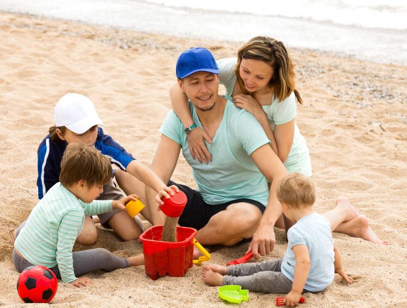 快乐的父母和孩子们在海边玩沙子