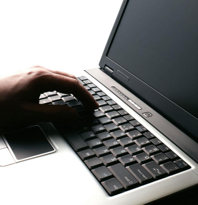 白色背景下一只手在黑色键盘上打字