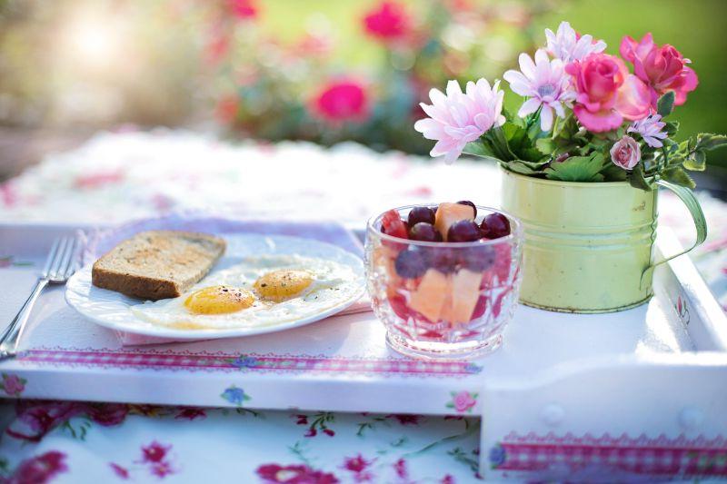 有鲜花和水果陪衬的盘中的面包煎蛋