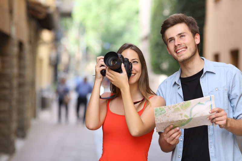 快乐的男女游客在老街上用数码相机拍照