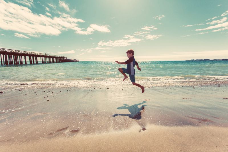 在海滩上跳跃的小男孩
