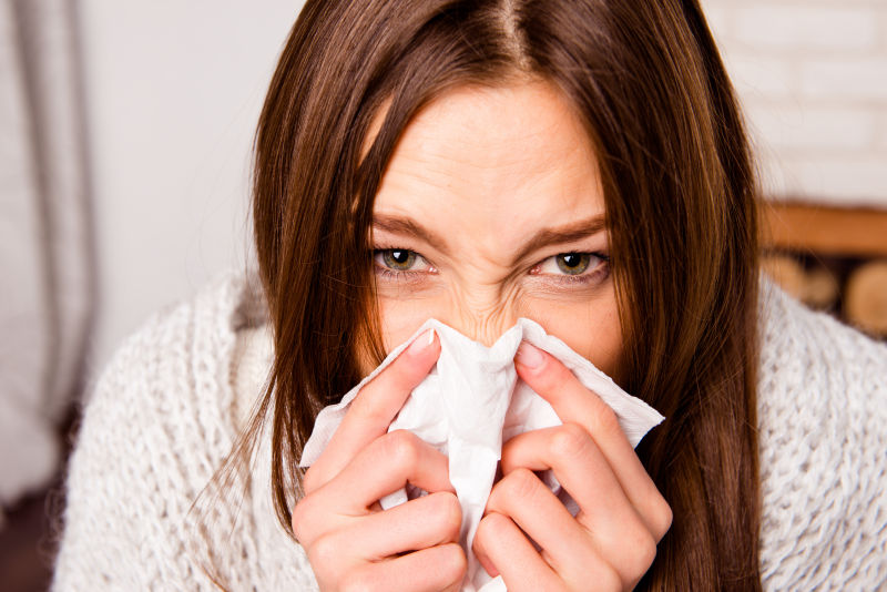 感冒的女人用纸巾擦鼻子