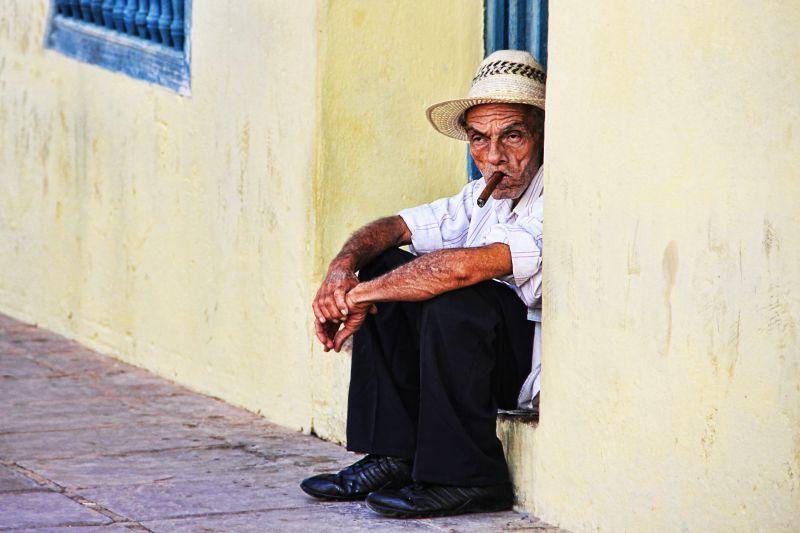 街道上坐在台阶上抽着雪茄的老人