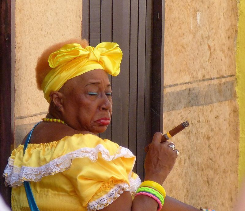 穿着黄色衣服的非洲妇女抽着雪茄