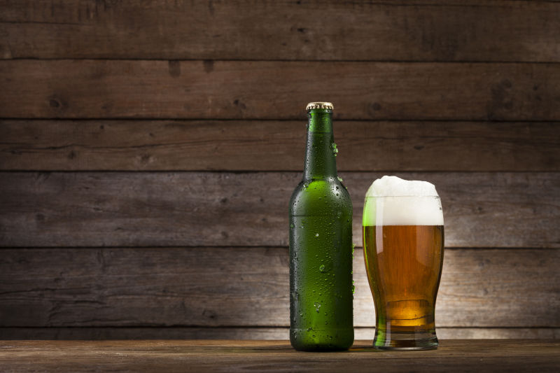 木板上放着一瓶啤酒和一杯啤酒