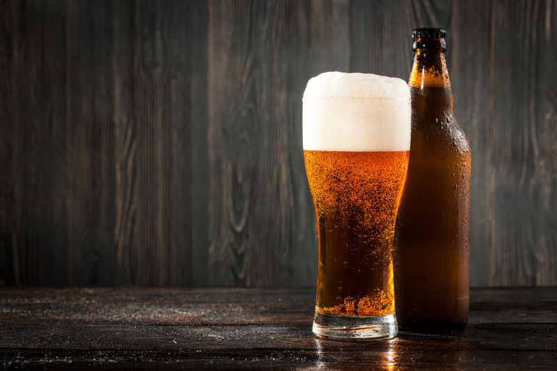木桌上装在啤酒杯和啤酒瓶的冰啤酒
