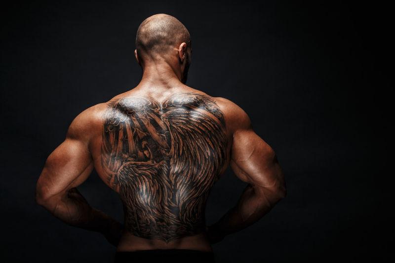 黑色背景上的纹身背部的肌肉男
