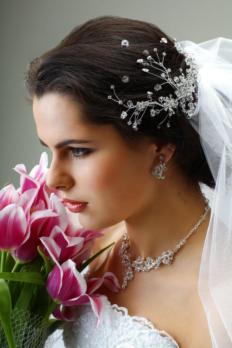 穿着白色婚纱的新娘带着珠宝饰品捧着鲜花