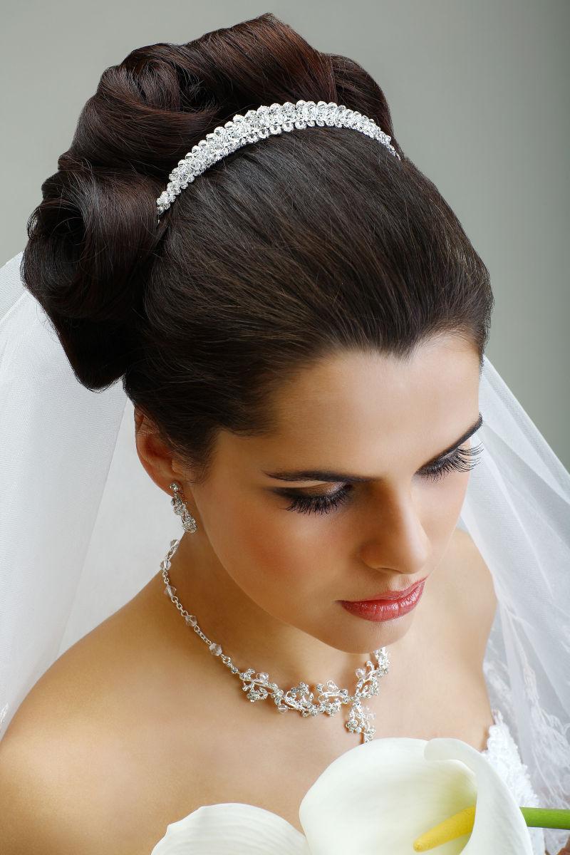 穿着白色婚纱的新娘带着精美的钻石发箍和项链