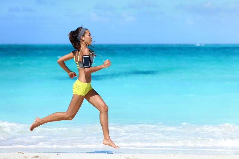 在海滩上听着音乐健身跑步的女子