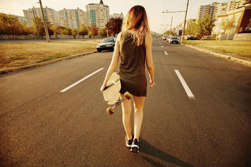走在公路上的滑板女孩