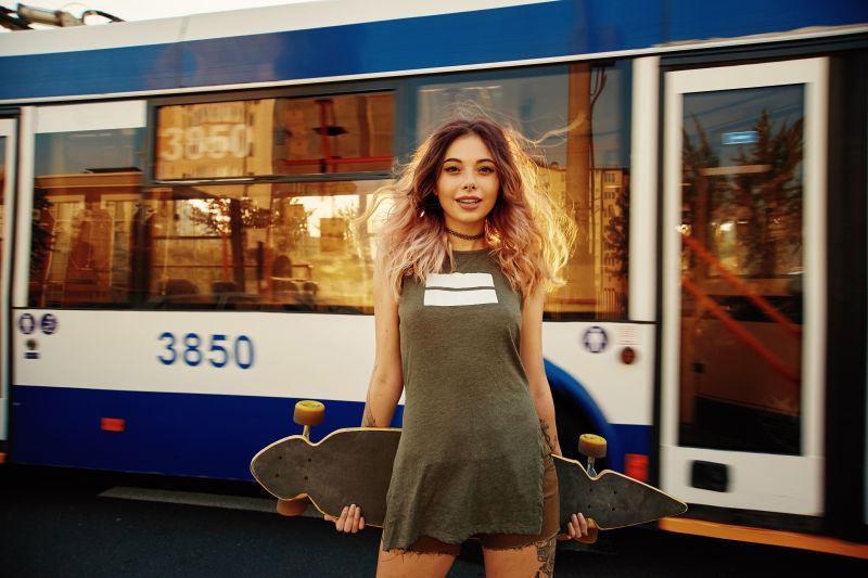 城市街道上拿着滑板的女孩