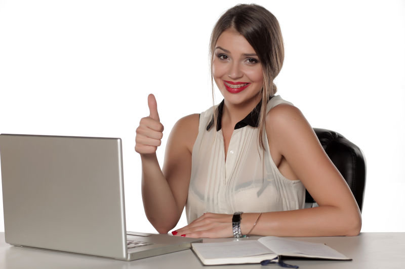 年轻女人坐在笔记本电脑前竖起大拇指
