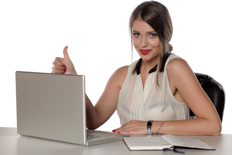 漂亮的女人坐在笔记本电脑前竖起大拇指