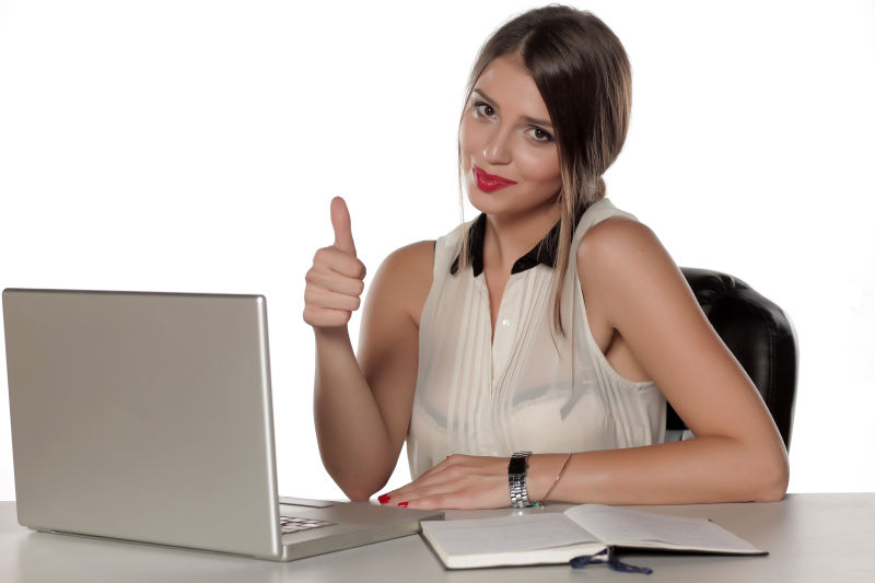 漂亮的女子坐在笔记本电脑前竖起大拇指