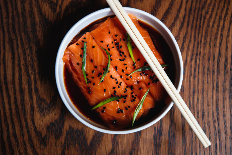 木桌上放置的筷子和碗中的日本式三文鱼