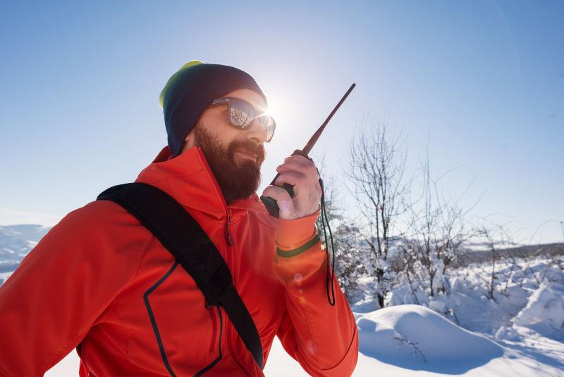 救援人员在山地雪景上用便携式收音机交谈