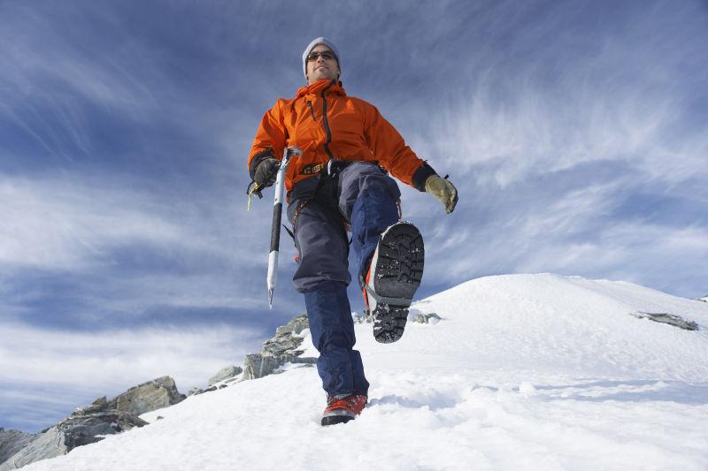 一位男子登山者在雪坡上行走的低角度视角