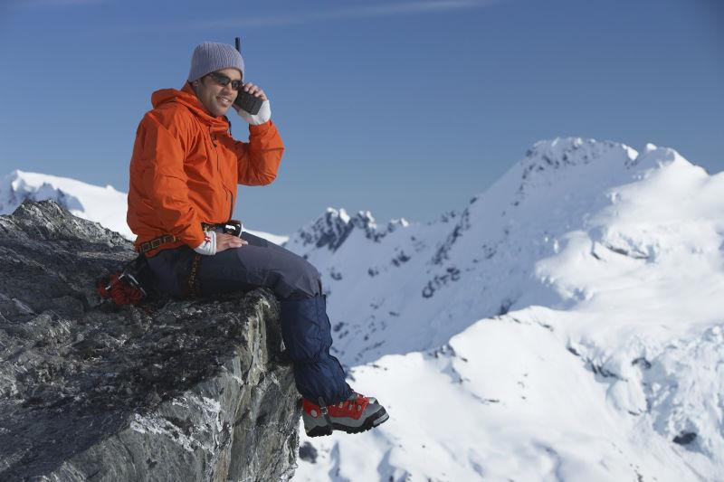山峰上使用对讲机的男性登山运动员