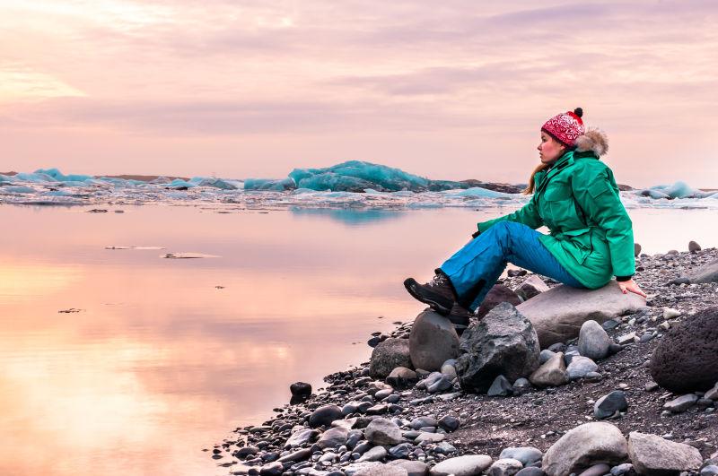 坐在冰岛冰川泻湖海滩上的女人