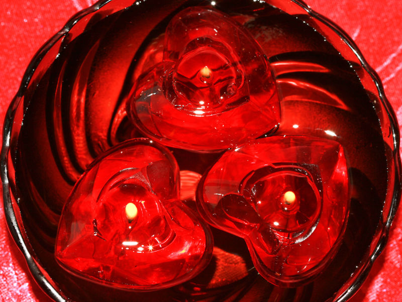 红色玻璃盘子上的三个心形蜡烛