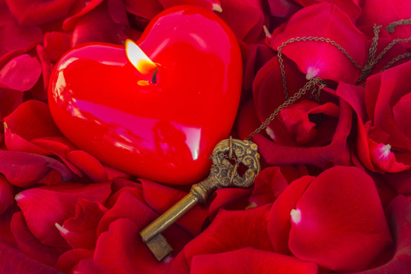 玫瑰花瓣上的心形蜡烛和钥匙