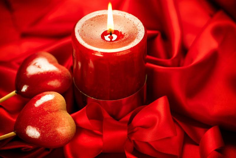 红色绸缎上的蜡烛和心形饰品