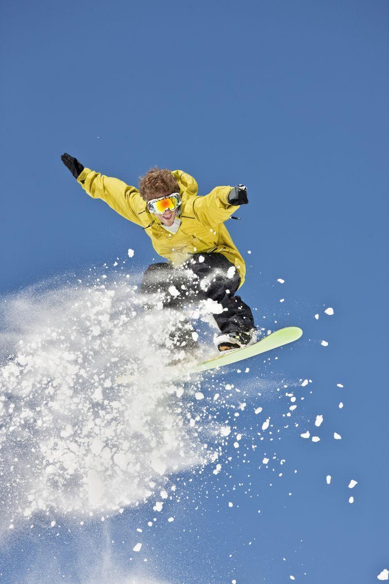 男子滑雪板在粉雪中跳跃
