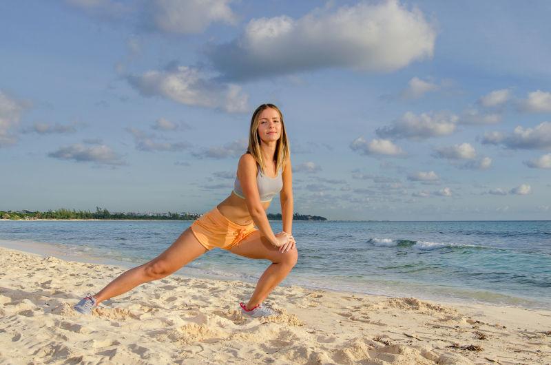在海滩上做柔韧运动的年轻女子