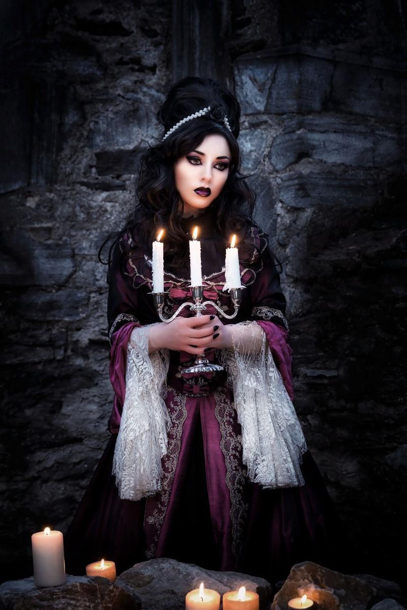 黑色背景中抱着蜡烛的哥特式女孩