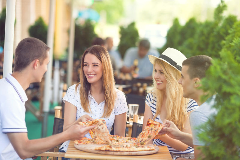 四个年轻朋友在咖啡馆户外享用比萨