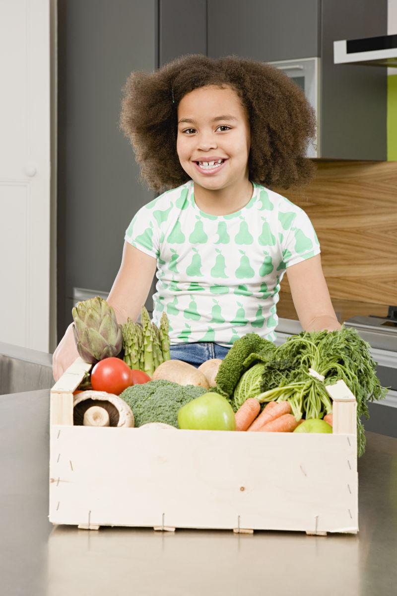小女和她面前装满蔬菜的箱子