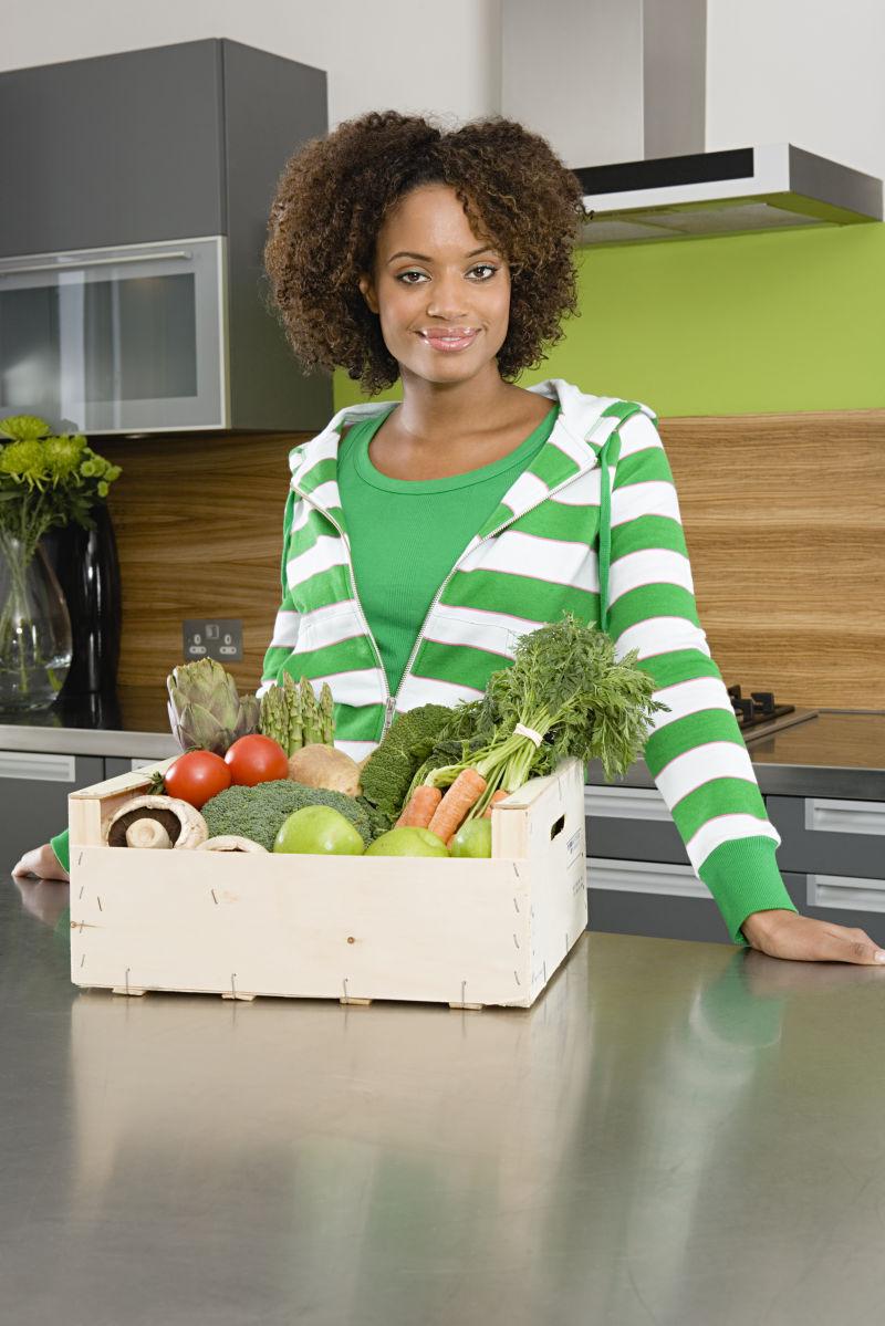 黑人妇女面前的蔬菜箱