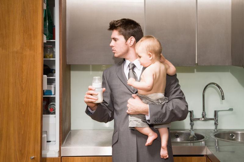厨房里的男子抱着婴儿准备奶粉
